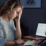 Mature and tired businesswoman working on computer until night. Portrait of a casual stressed lady with headache at desk.